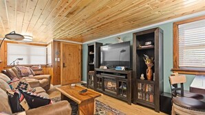 Una sala de estar acogedora con chimenea, techo de madera y asientos cómodos.