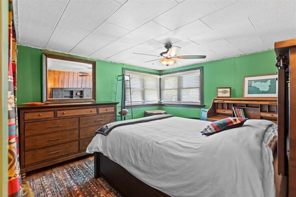 A bedroom with a bed, dresser, and a ceiling fan.