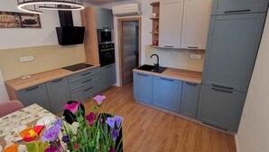 A modern kitchen with grey cabinets, a wooden countertop, and a black sink.