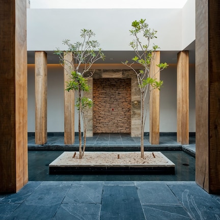 A modern interior with wooden pillars, a stone wall, and a small water feature.