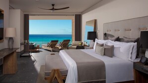Habitación de hotel moderna con una cama grande, un escritorio, una silla y vista al océano.