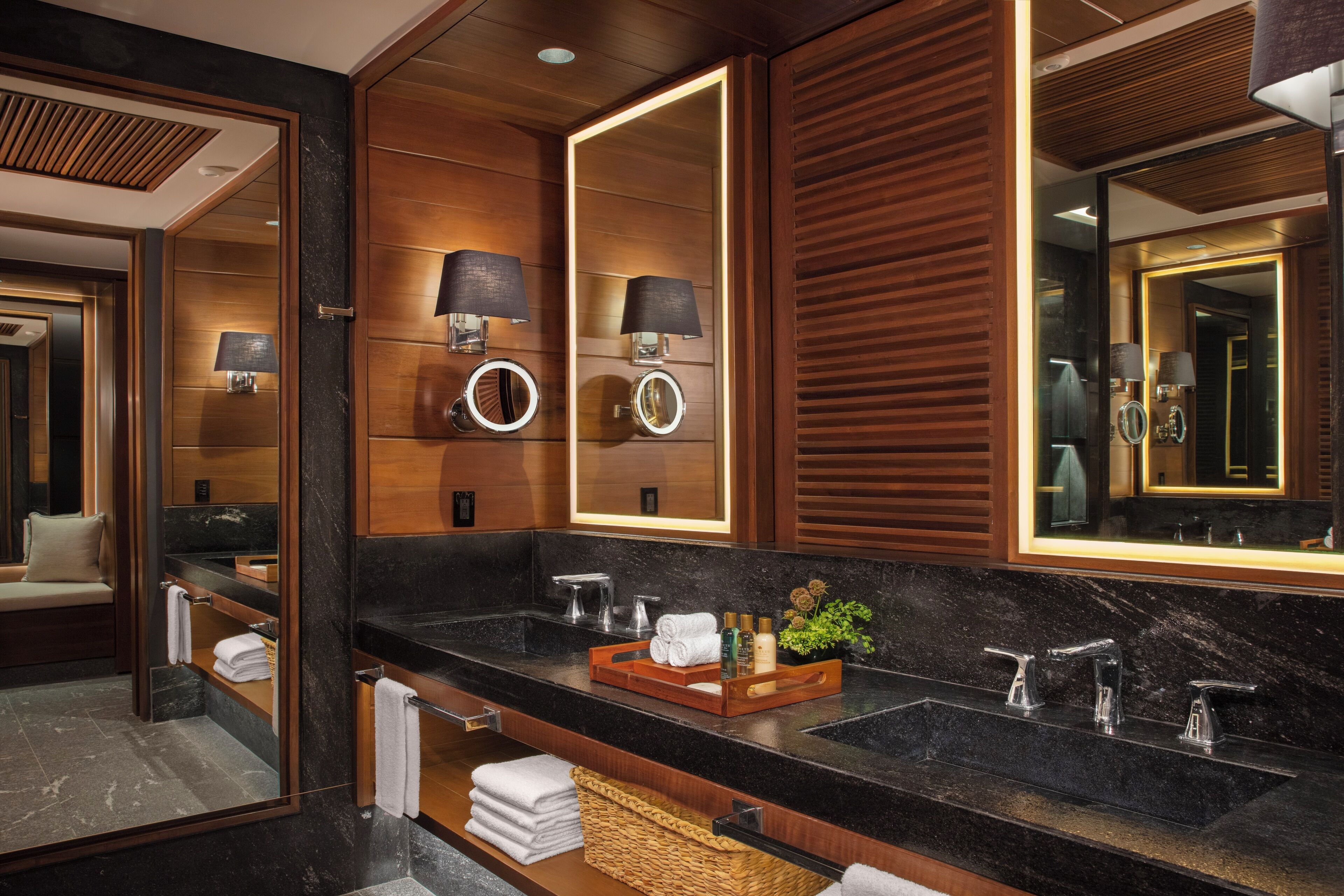 Une salle de bain moderne avec deux lavabos, de grands miroirs et un lambris en bois.
