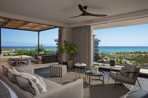 Ein modernes Wohnzimmer mit einem großen Fenster mit Blick auf einen Strand und den Ozean.