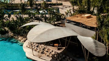 A resort with a large pool, lounge area, and thatched-roof structures.
