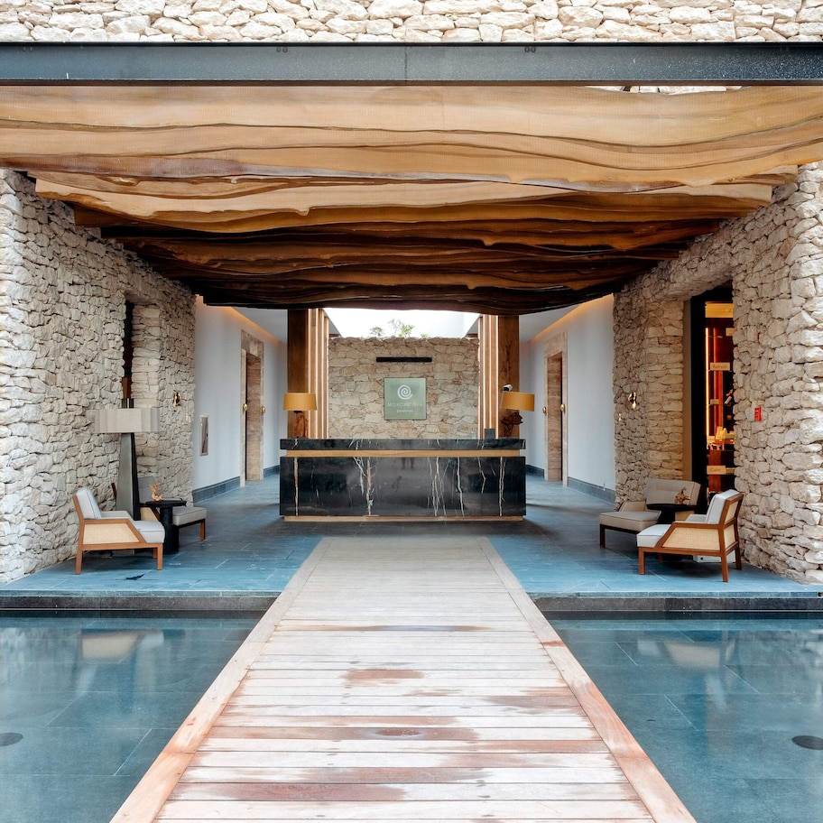 A stone-walled pool area with a wooden deck leading to a reception desk.