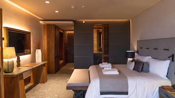 Una habitación de hotel moderna con una cama grande, mesitas de noche, un banco y un escritorio con lámpara.
