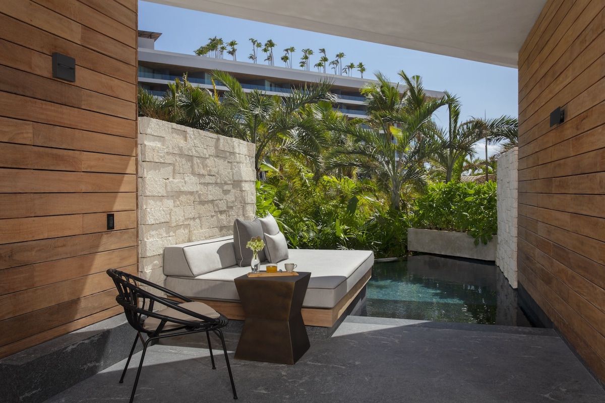 Ein moderner Außenbereich mit einer Sitzecke, einer Couch und Sesseln, einem kleinen Tisch und einem Pool.