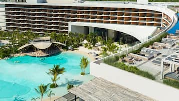 A modern resort with a large pool, multiple balconies, and a beach area.