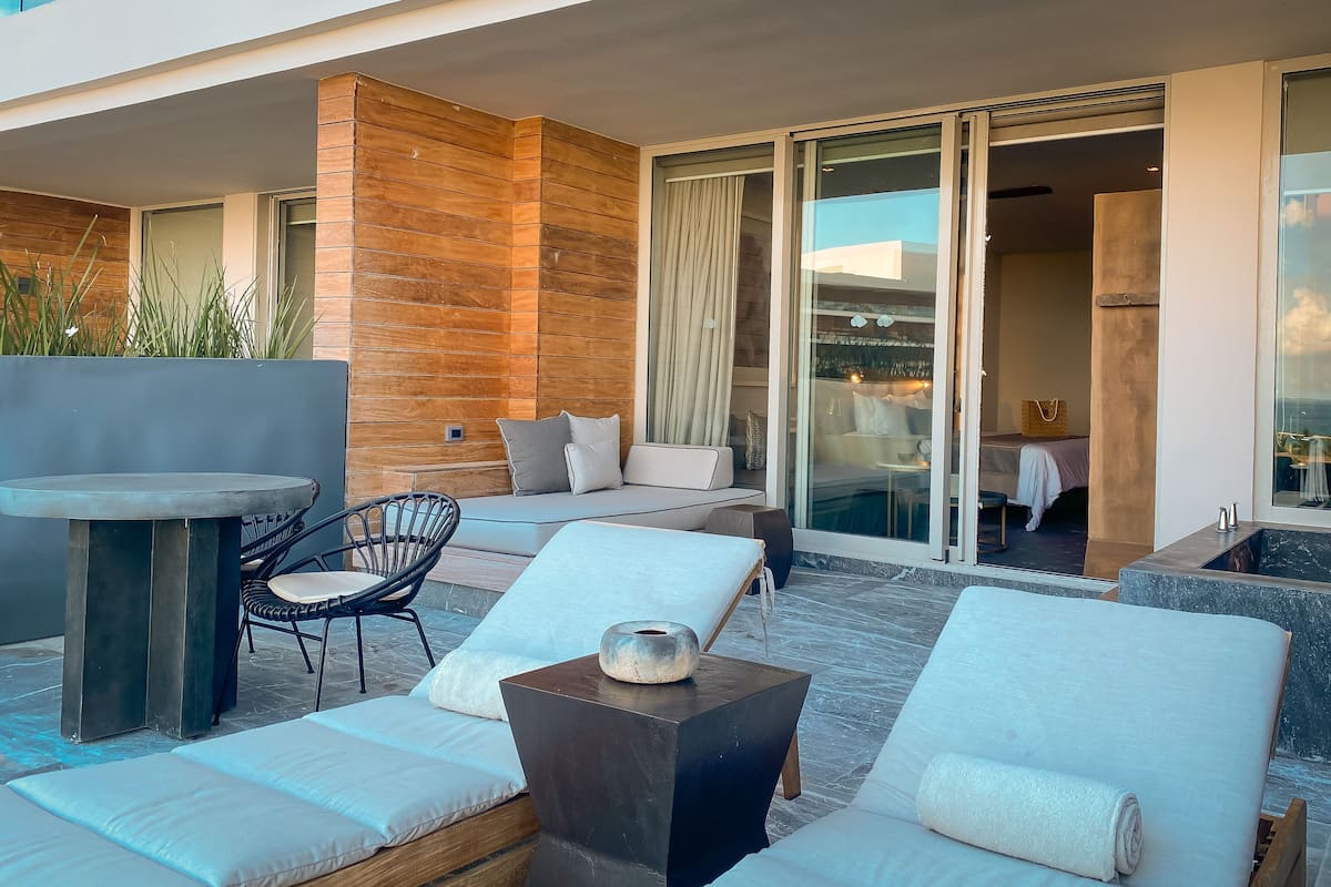 Un espacio al aire libre moderno con sofá, sillas y una mesa.