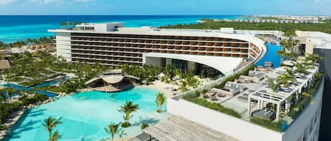A resort with a large pool, multiple balconies, and a view of the ocean.