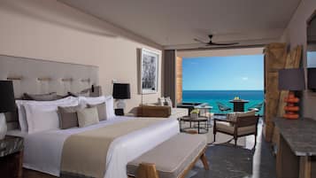 A modern hotel room with a large bed, a desk, a chair, and a view of the ocean.