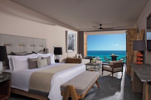 Une chambre d’hôtel moderne dotée d’un grand lit, d’un bureau, d’une chaise et offrant une vue sur l’océan.