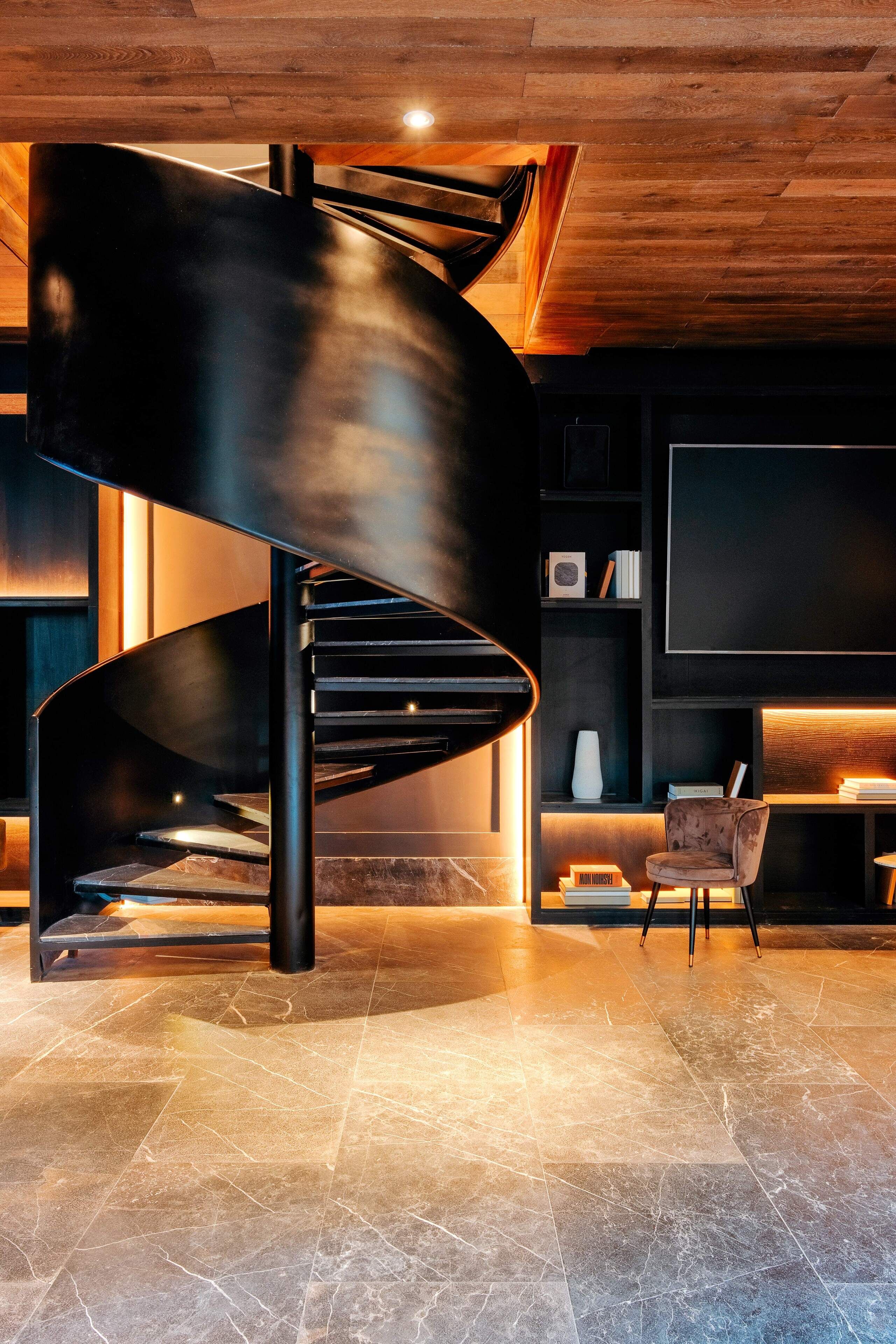 A modern interior with a spiral staircase, a flat-screen TV, and a plush chair.