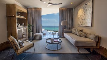 Una sala de estar moderna con sofá, sillón, mesa de centro y vista al océano.