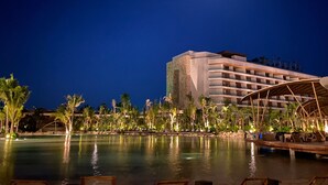 Een resort met een zwembad, palmbomen en een gebouw met meerdere balkons.