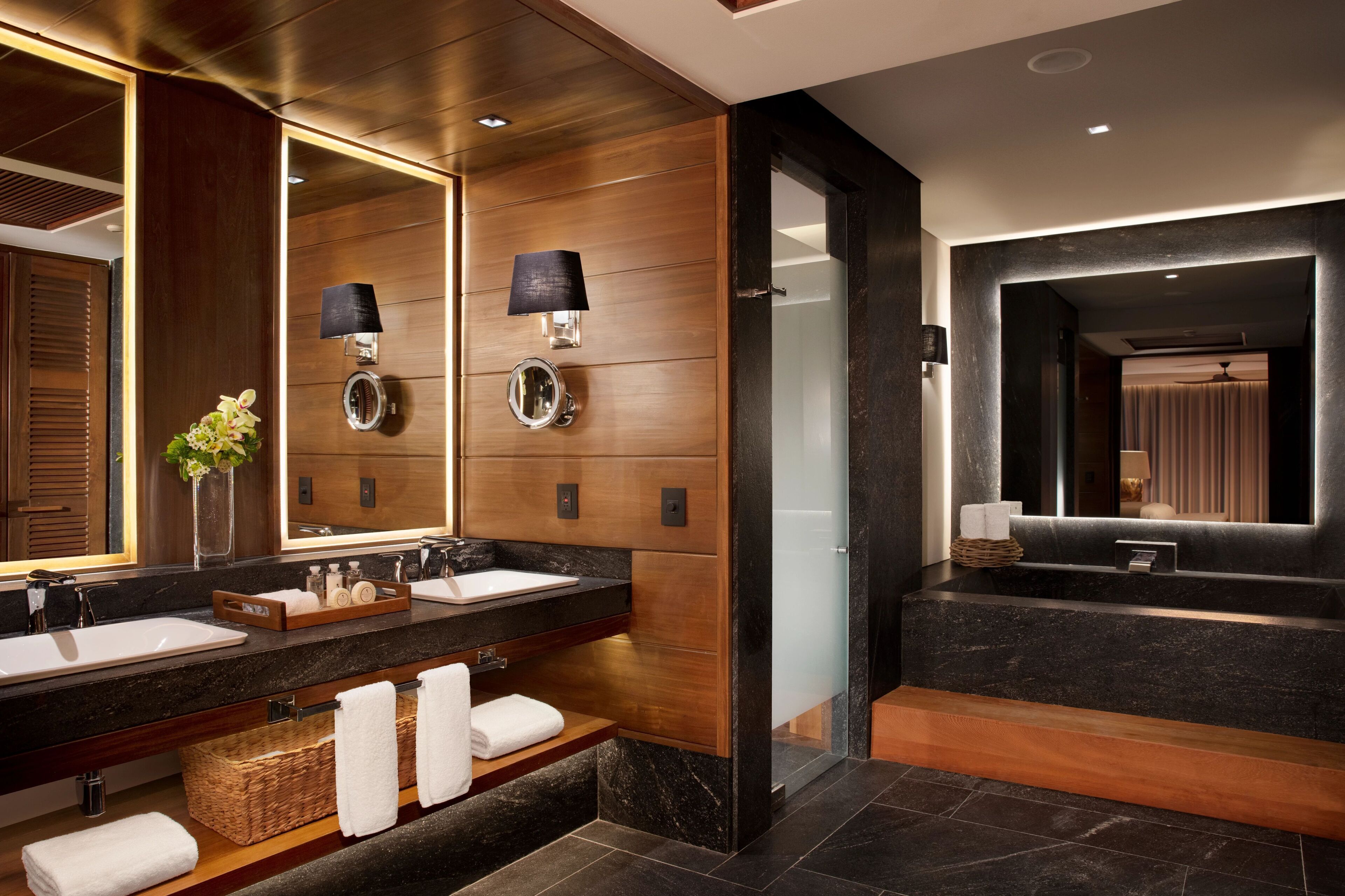A modern bathroom with dual sinks, a large mirror, and a walk-in shower.