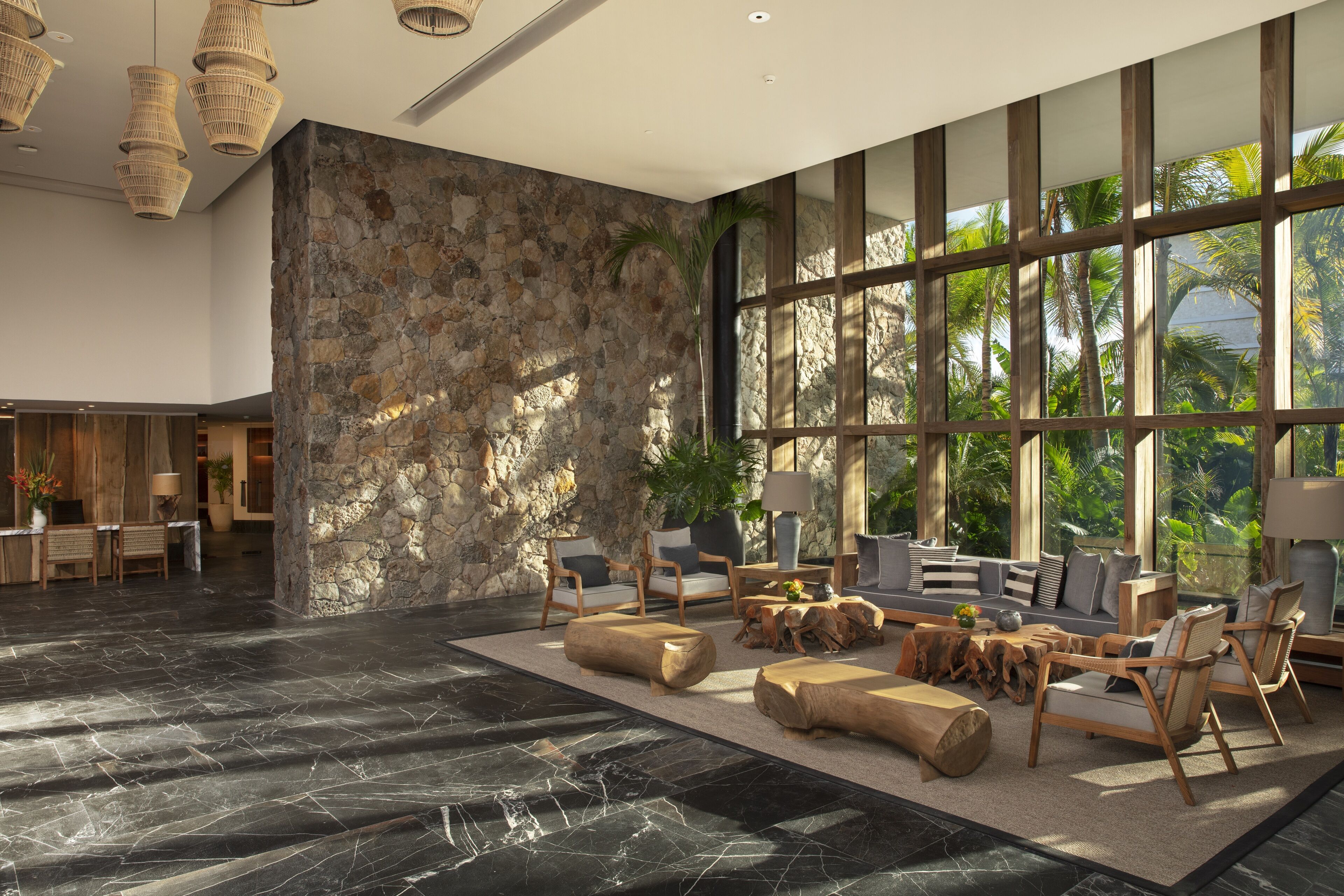 A spacious lobby with a stone wall, large windows, and modern furniture.