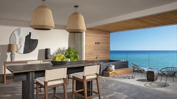 A modern kitchen with a large island, bar stools, pendant lights, and a view of the ocean.