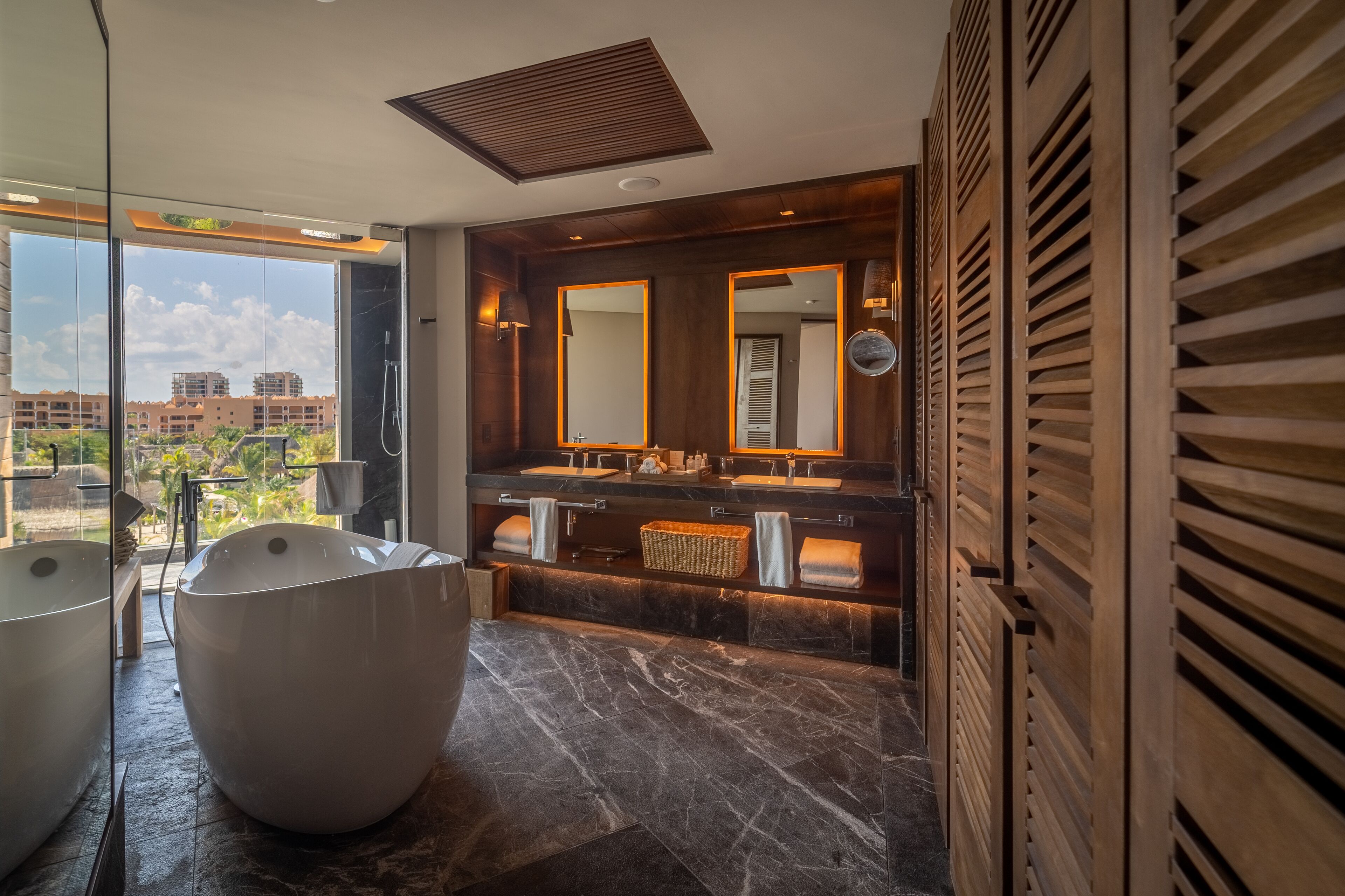A modern bathroom with a large bathtub, two sinks, and a large mirror.