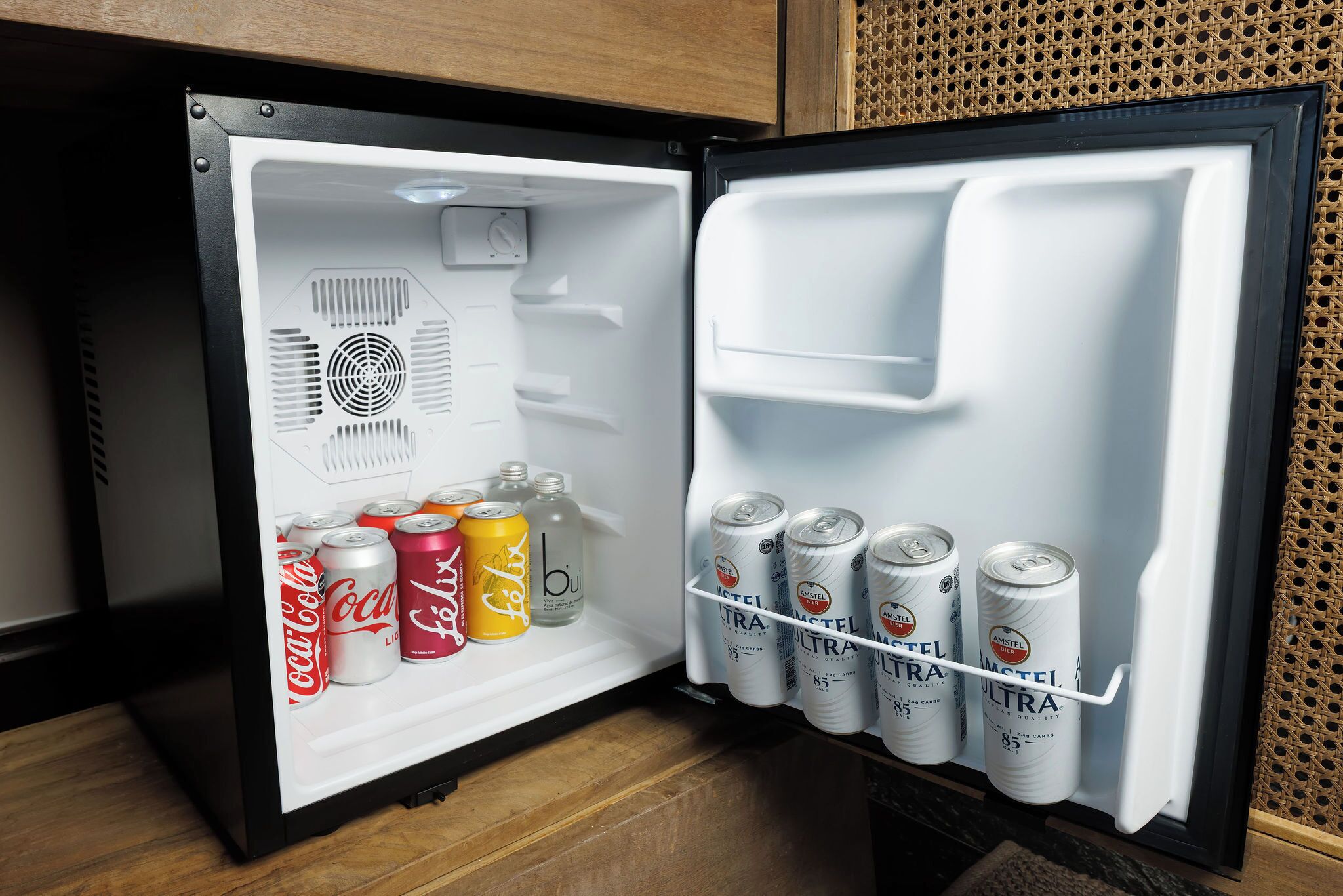 A refrigerator with a shelf containing various beverages and a door with a beverage dispenser.