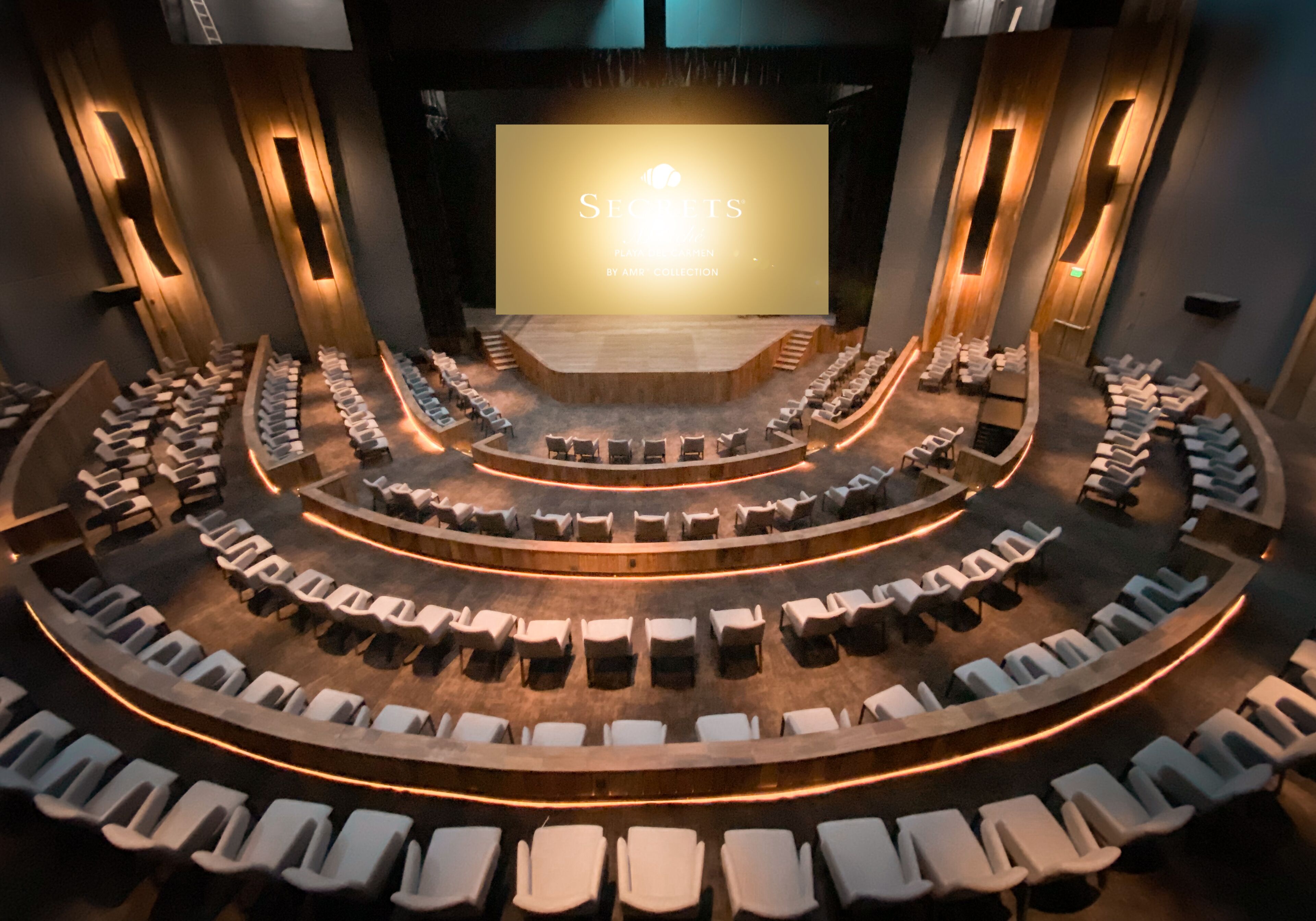 A theater with a curved seating arrangement and a large screen at the front.