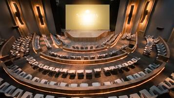 A theater with a curved seating arrangement and a large screen at the front.