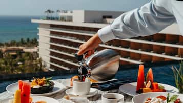 A table with a variety of dishes and a person pouring a drink.