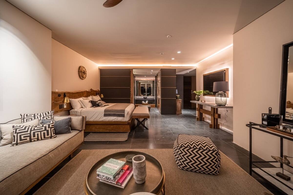 Une chambre d’hôtel moderne, équipée d’un canapé, d’un lit, d’une table basse avec des livres et d’un élément décoratif mural.