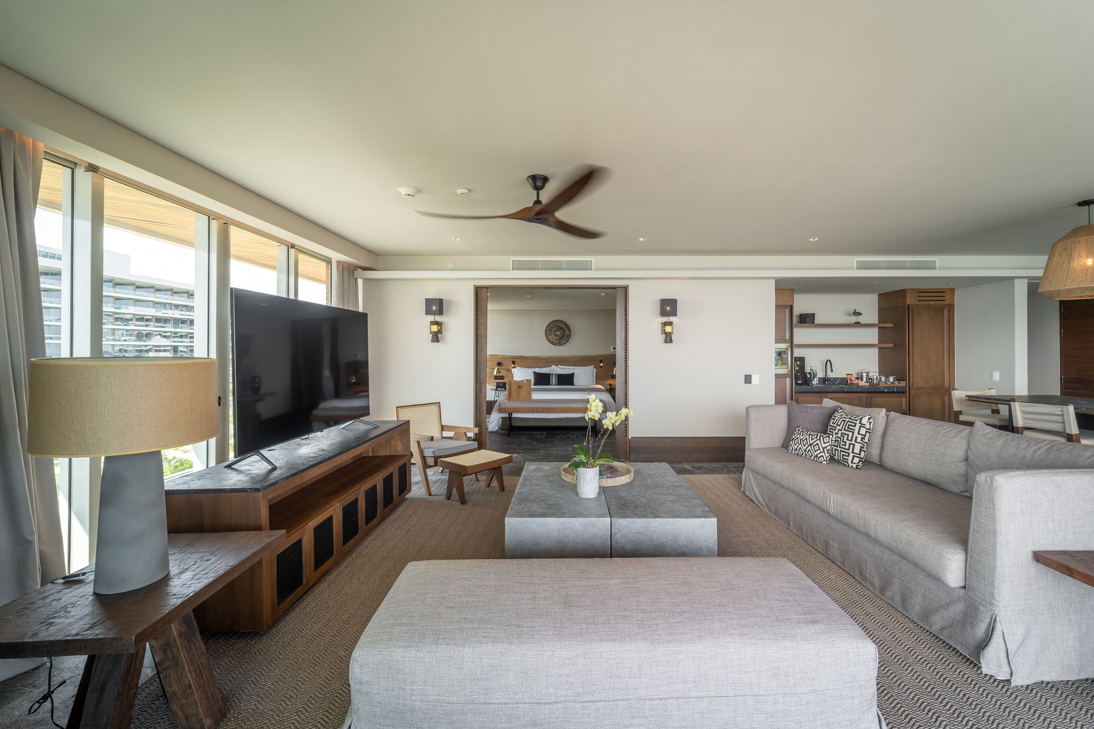A modern living room with a flat-screen TV, a sofa, a coffee table, and a dining area.