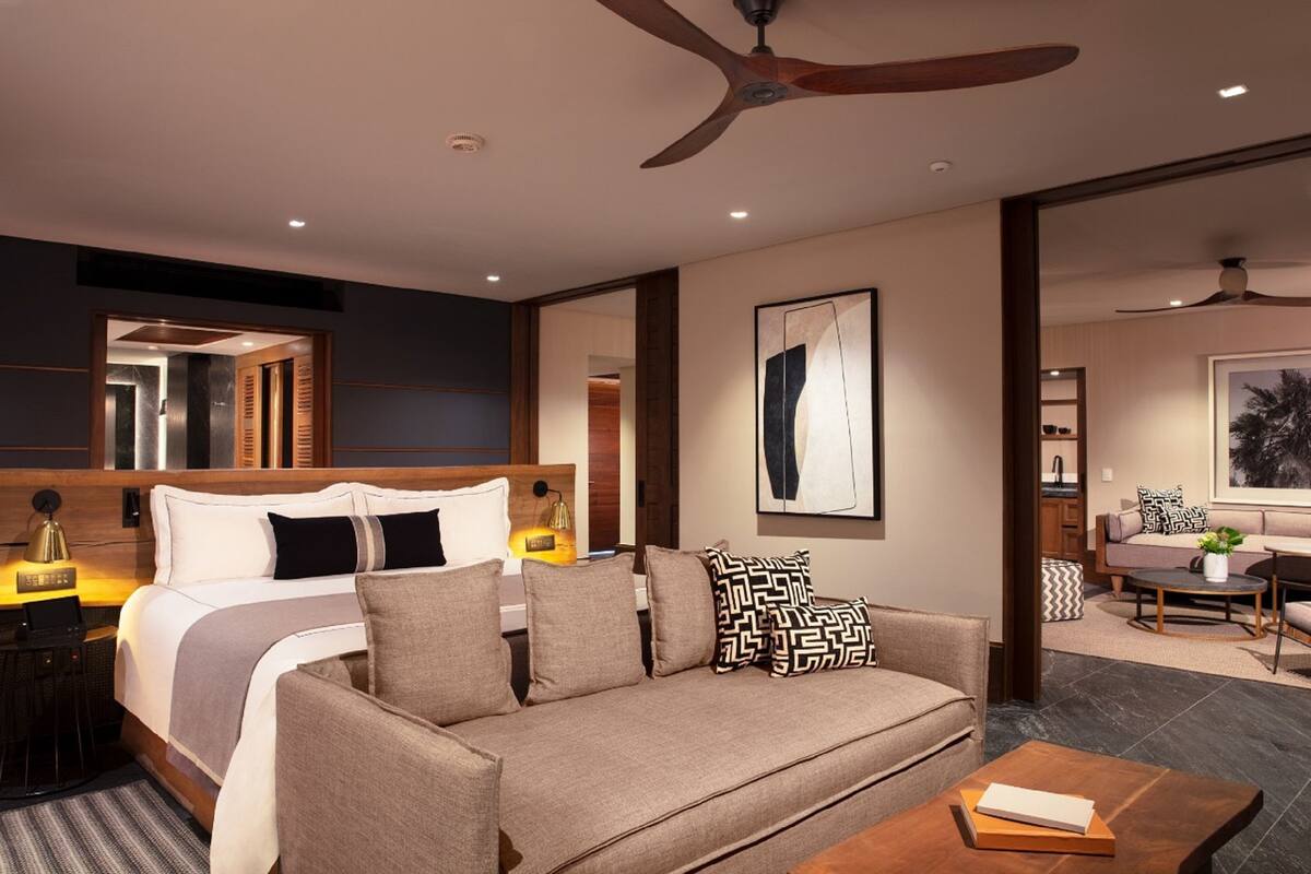 Une chambre d’hôtel moderne équipée d’un lit, d’un canapé, d’une table basse et d’un ventilateur de plafond.