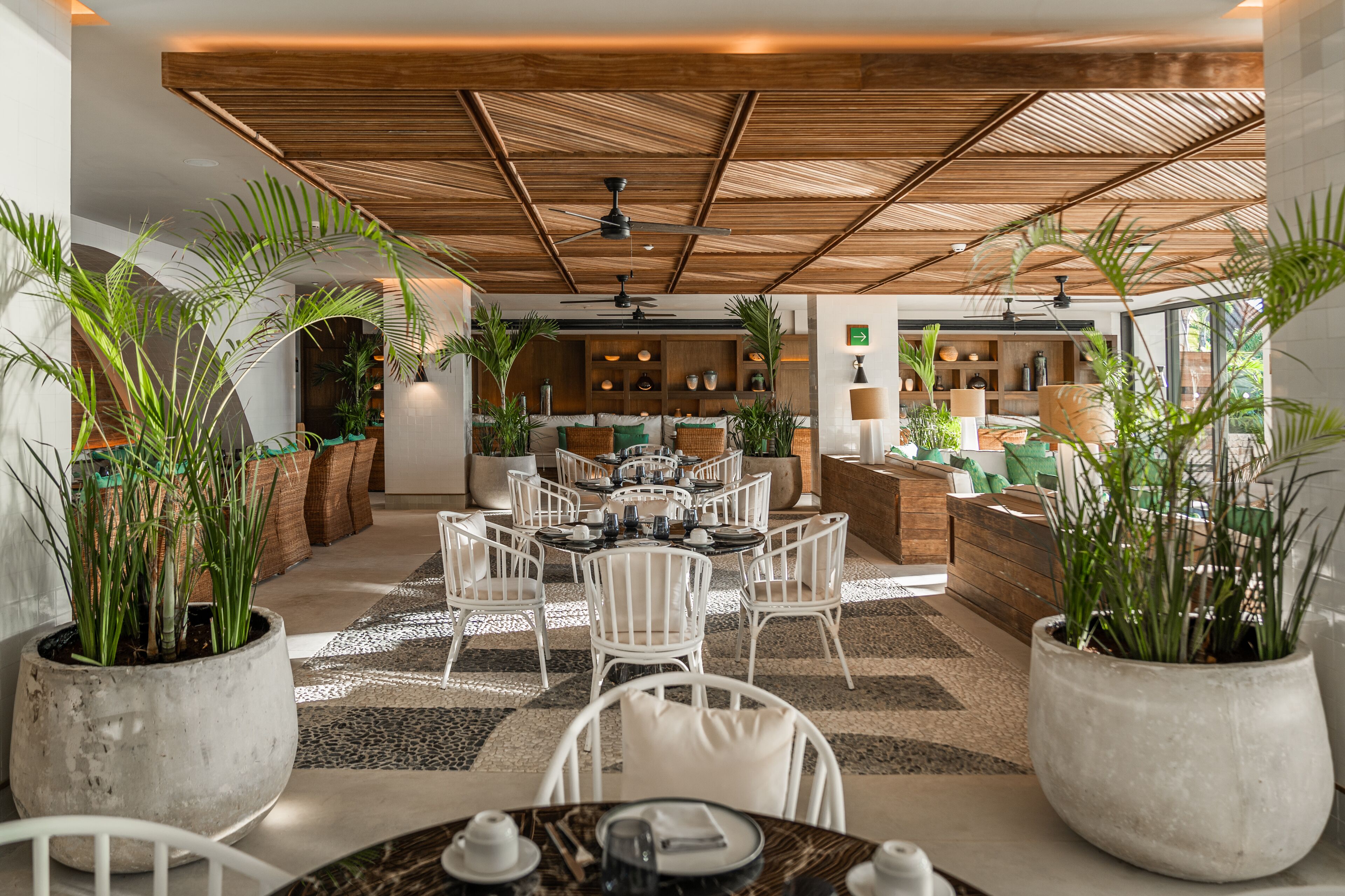 A modern dining area with white chairs, a round table, and potted plants.