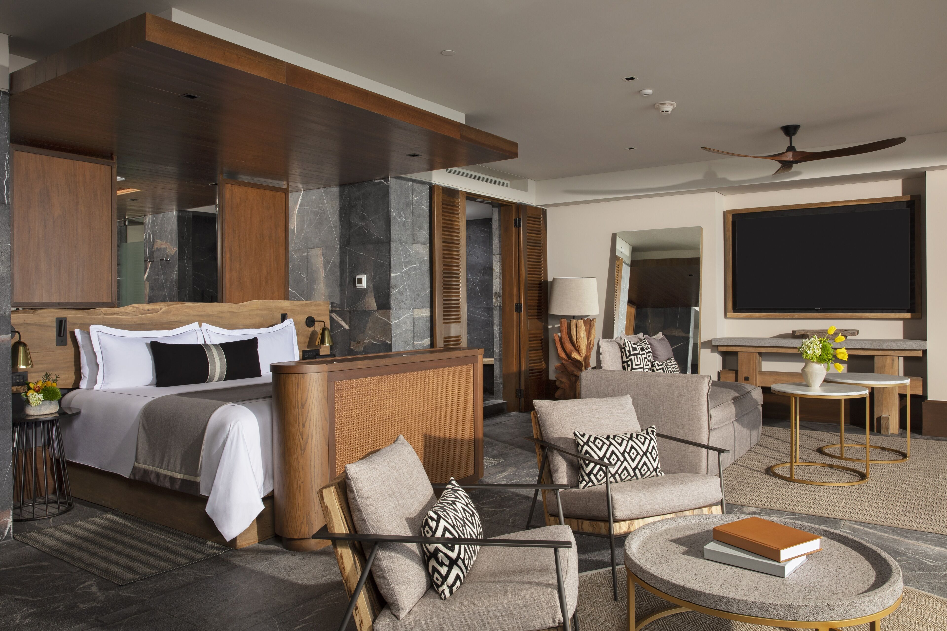 A modern hotel room with a bed, seating area, and a television.
