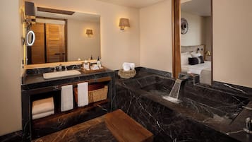 A modern bathroom with a large mirror, two sinks, a bathtub, and a wooden bench.