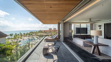 Un balcon avec vue sur une piscine et une plage, aménagé avec des chaises et un canapé.