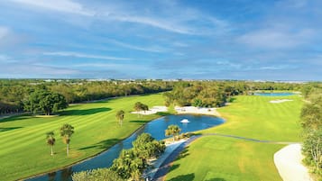 Un parcours de golf agrémenté d’un plan d’eau, de bunkers de sable et offrant une vue sur un ciel dégagé.