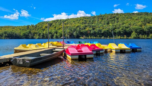 A lake with colorful paddle boats docked at the shore. - Mountain condo by Okemo w/ hot tub (Ludlow)