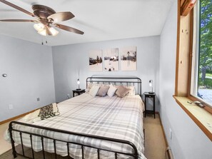 Ein Schlafzimmer mit Bett, Deckenventilator, Nachttischlampen und Kunstwerken an der Wand.