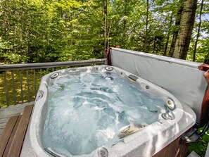 Ein Whirlpool auf einer Holzterrasse, umgeben von üppigem Grün.