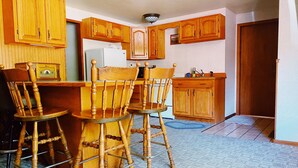 A kitchen with wooden cabinets, a refrigerator, and a bar stool. - Julieann's in Alaska - Home in the Heart of Sitka (Sitka)
