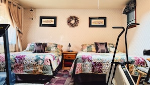 A bedroom with two beds, a desk, a chair, a radiator, and a ceiling fan. - Julieann's in Alaska - Home in the Heart of Sitka (Sitka)