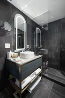 Un baño moderno con un espejo grande, un lavabo redondo y una ducha con mampara de vidrio.