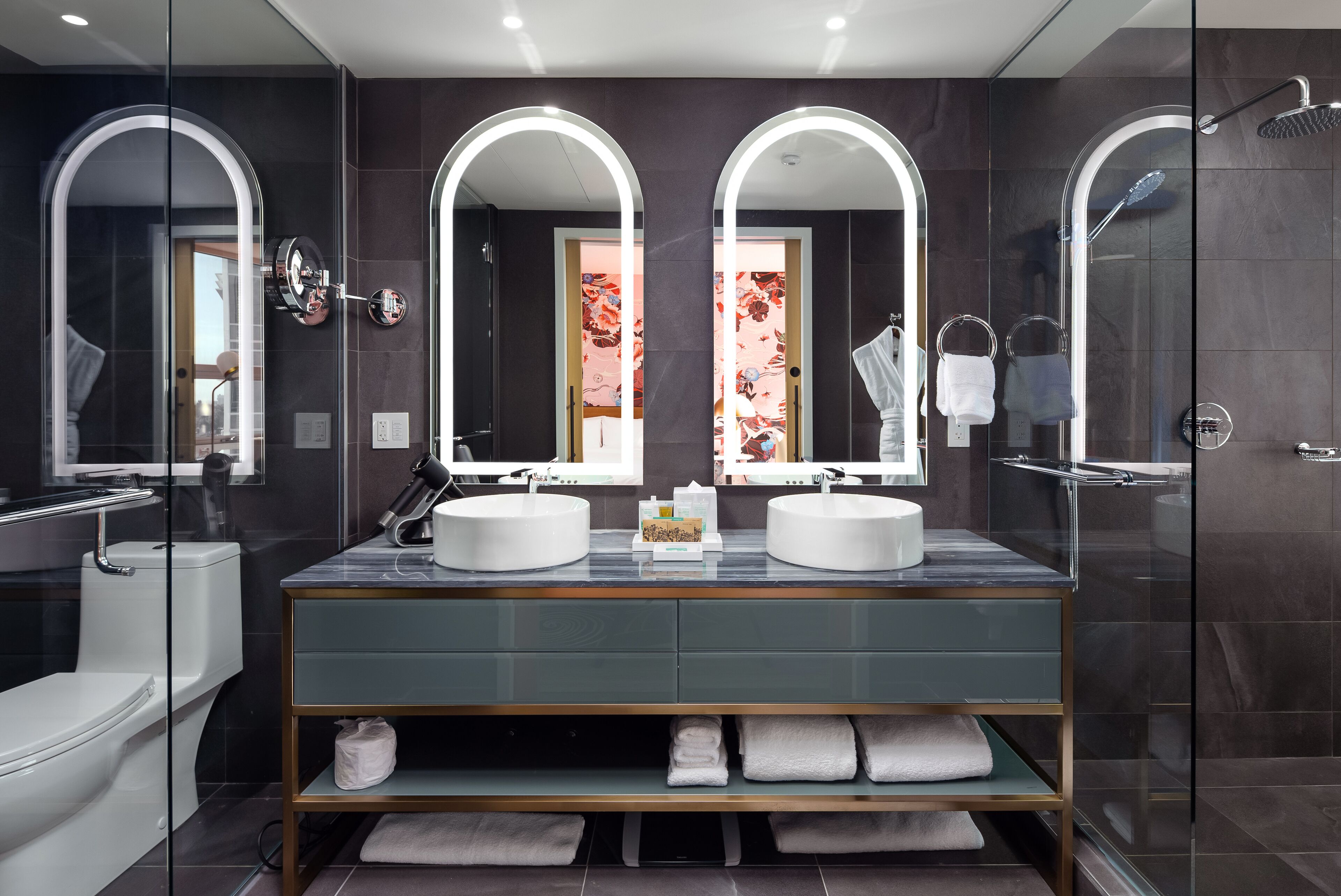 A modern bathroom with two sinks, a glass shower enclosure, and a vanity with a mirror.
