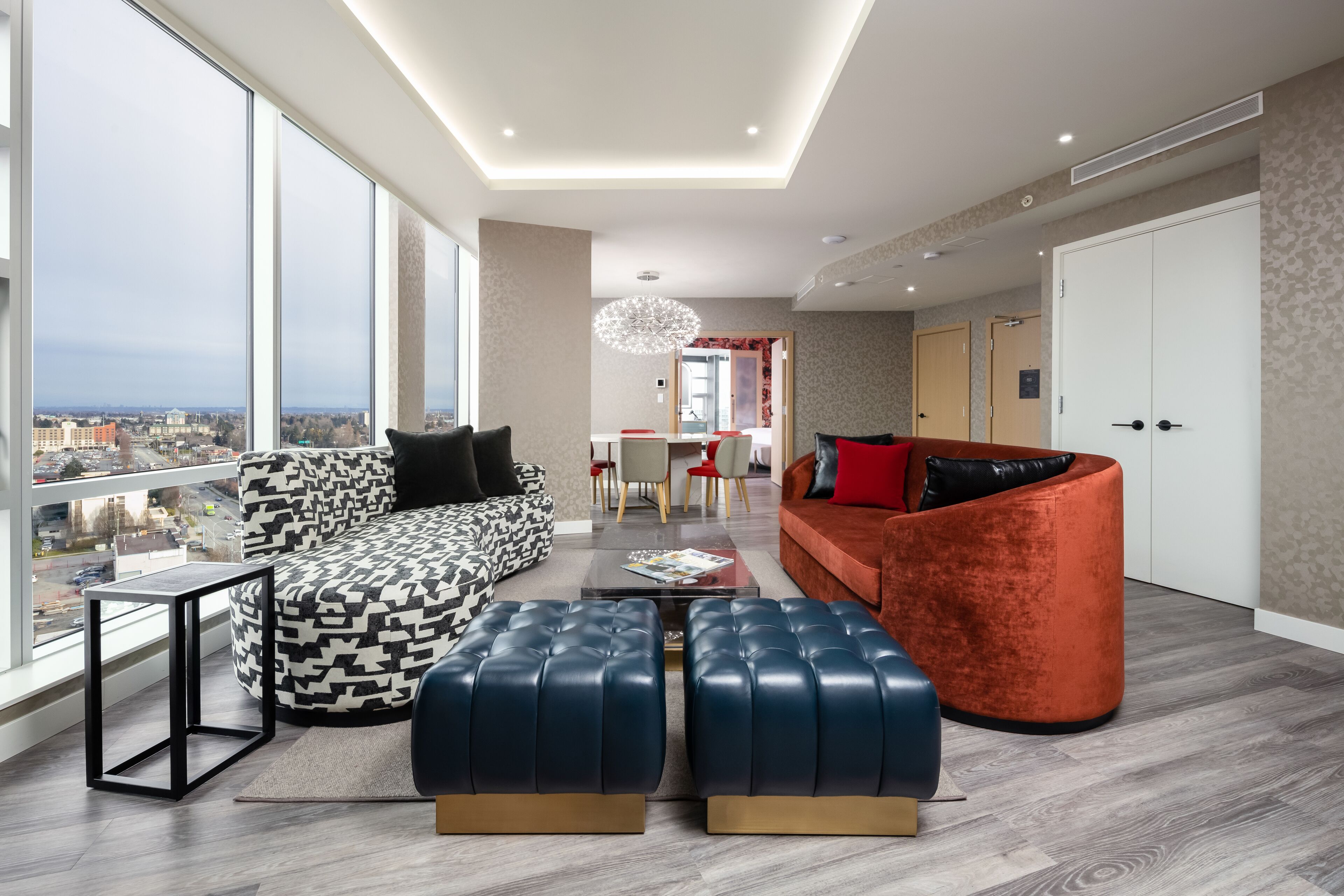 Una sala de estar moderna con sofá, reposapiés y una zona de comedor con sillas y mesa.