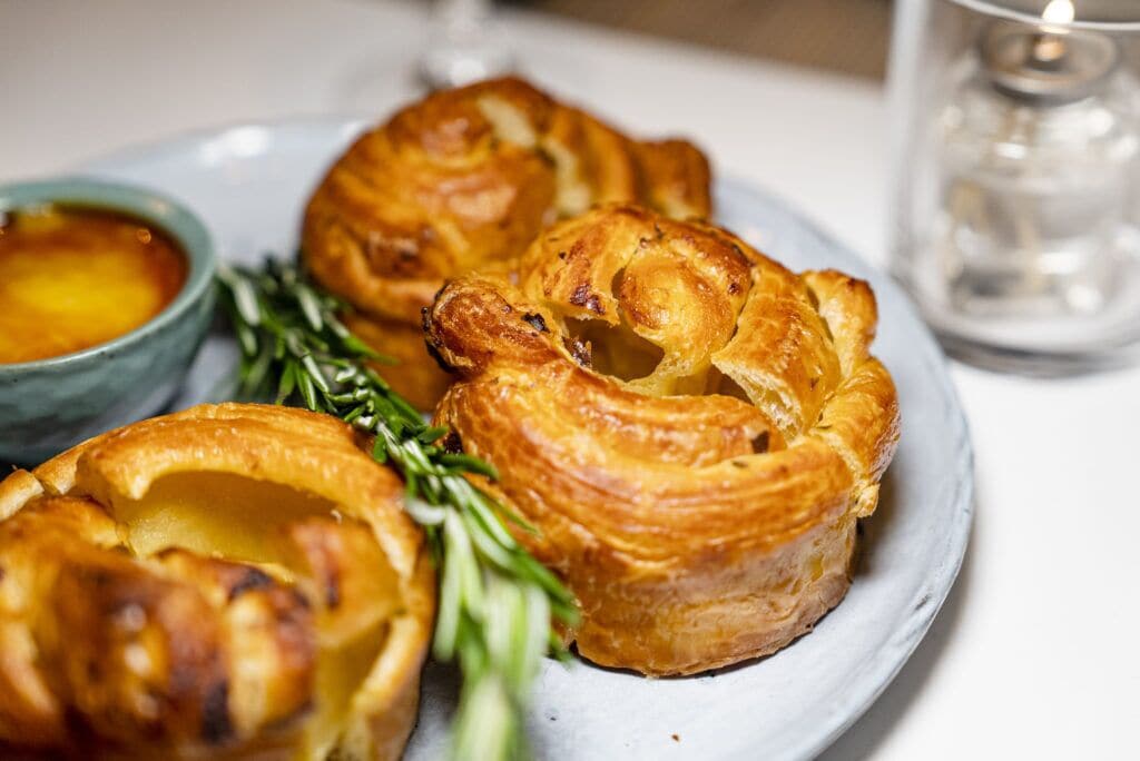 Un piatto di Yorkshire pudding servito con salsa gravy e rosmarino.
