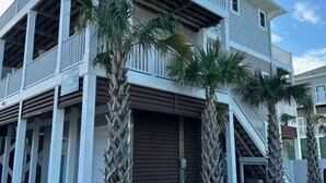 Una casa de dos pisos con balcón, palmeras y garaje.