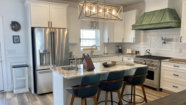 Una cocina moderna con una isla central, electrodomésticos de acero inoxidable y taburetes de bar.