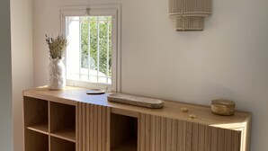 A wooden console table with a vase of flowers, a small round table, and a wall-mounted light fixture. - Superb house on the ROOF, Terrace with SUPERB VIEW on the CANALS and JACCUZZI (Grimaud)