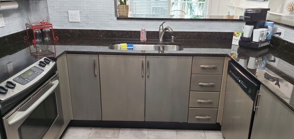A modern kitchen with stainless steel appliances, a sink, and a coffee maker.