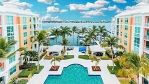 Een resort met een centraal gelegen zwembad, palmbomen en uitzicht op de oceaan.