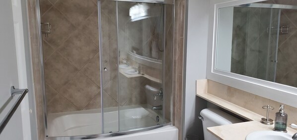 A bathroom with a glass-enclosed shower, a sink, and a mirror.